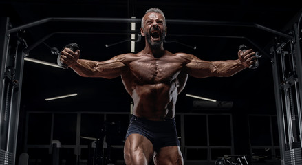 Fototapeta na wymiar Brutal adult athlete posing in the gym.