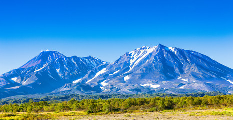 Fototapeta premium Panorama of Kamchatka volcanoes: Avachinsky and Kozelsky volcanoes in Kamchatka in the autumn with a snow-covered top