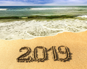 New 2019 year in the South, the sea. Sea surf. Blue wave is coming ashore. Inscription on sand, celebrate new year in the tropics. New year holidays