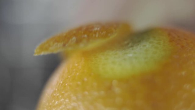 Removing of orange peel from the orange with a knife. Citrus zester grating peeling orange peel, oils spraying.