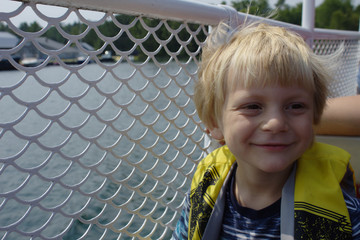 Cute Young Blond School Aged Boy Smiling on a Boat on the Lake in the Summer