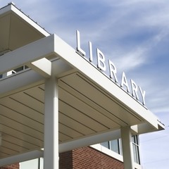 White library sign with blue slightly cloudy sky in the background