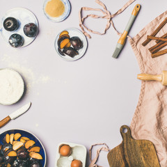 Baking ingredients and tools. Flat-lay of dusty pink linen apron, kitchen utensils, flour, sugar, fruit and spices over pastel lilac background, top view, copy space, square crop