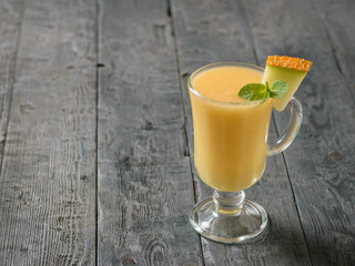 Glass mug with a smoothie of melon on rustic table.