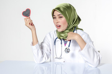 Smiling female doctor holding heart shape  studio portrait isolated on white background