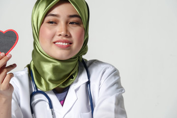 Smiling female doctor holding heart shape  studio portrait isolated on white background