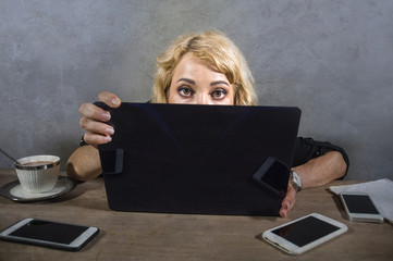 young surprised and stressed business woman at office desk looking intense to computer screen surrounded by mobile phones in overwork