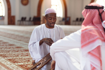 Muslim men praying with holy books in mosque