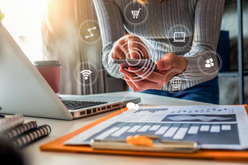 Women use the phone and work papers at the table.