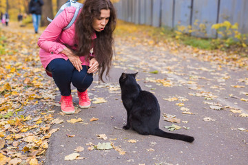 People, pets and season concept - young woman and a cat in the autumn park