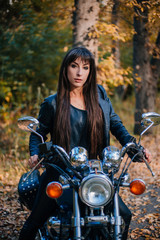 Fototapeta na wymiar Girl on a motorcycle in a black jacket and leather pants. Women biker