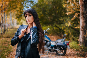 Plakat The girl in a black leather jacket with long hair. Motorcycle in the background
