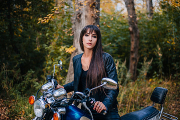 Plakat Girl on a motorcycle in a black jacket and leather pants. Women biker