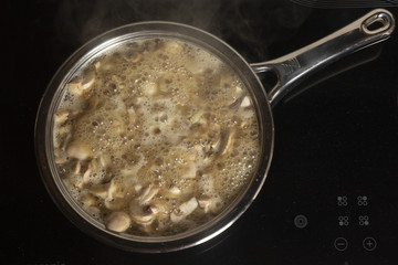 Roasting of champignon mushrooms  in butter on a frying pan on the stove