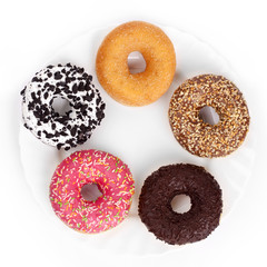 Multicolored donuts on a white plate on a white background top view
