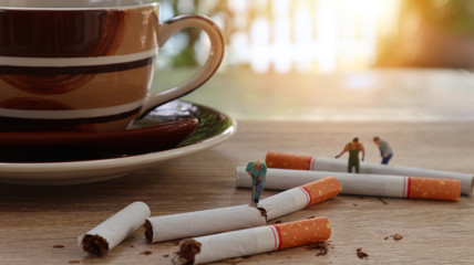 Miniature stop smoking concept, Group of miniature mini figures with destroy cigarettes on cup of cofee background