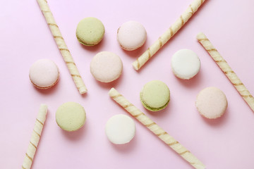 Obraz premium French macaroons and crispy wafer rolls on pink background.
