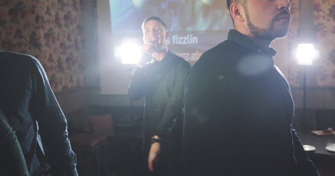 A young man is singing in a karaoke club.
