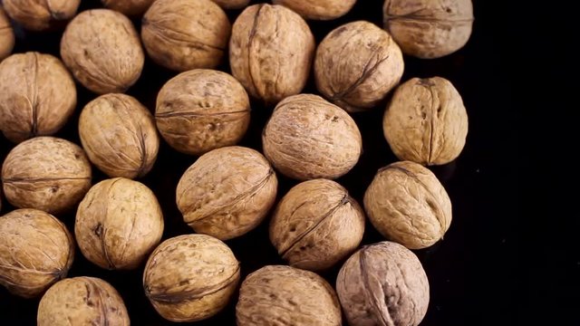 Close up of walnuts rotating on black surface background.