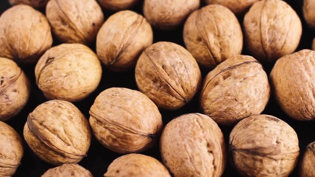 Close up of walnuts rotating on black surface background.