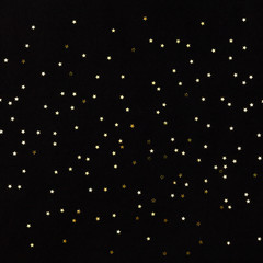 Top view on golden small stars on black background. Winter, Christmas celebration, holidays season concept