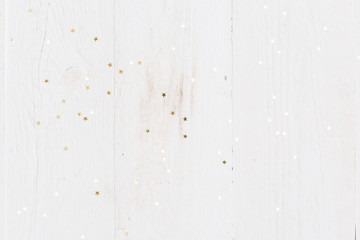 Top view on golden stars confetti on old white wooden background. Winter, Christmas celebration, holidays season concept