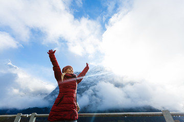Fototapeta na wymiar Winner. Success concept. Hiker woman cheering elated and blissful with arms raised in the sky after hiking to mountain top summit above the clouds.