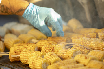 A person cooking corn on a grill in smoke