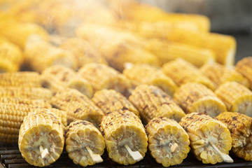 Corn cooking on a grill in smoke