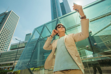 Fashion man makes selfie in the big city against the background of skyscrapers. Travel and life style concept.