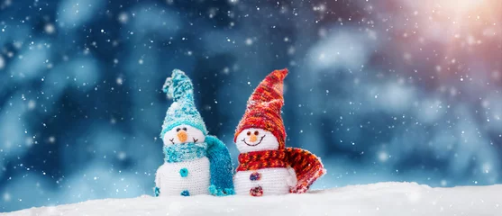 kleine gestrickte Schneemänner auf weichem Schnee auf blauem Hintergrund © candy1812