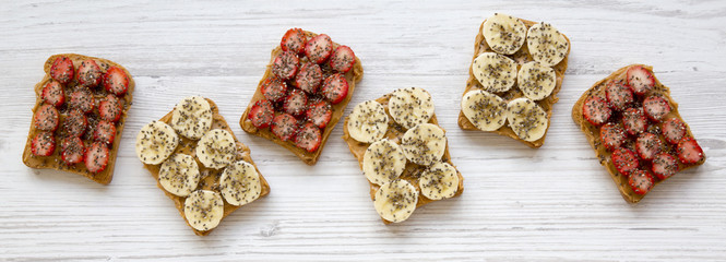 Vegan toasts with peanut butter, fruits and chia seeds on a white wooden table, overhead view. Healthy breakfast, dieting concept. Close-up.