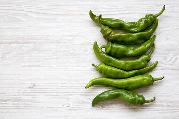 Green chili peppers on white wooden background, top view. Flat lay, from above, overhead. Copy space.