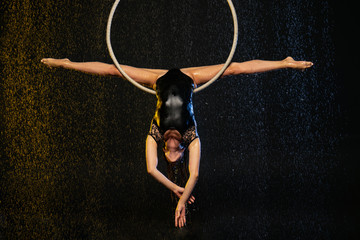 A young girl performs the acrobatic elements in the aerial hoop. Black Aqua Studio