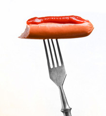 Sausage with ketchup on metal fork.