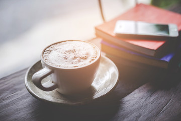 Close up of a cup of cappuccino or latte coffee with a foam white on a wooden background in a cafe.