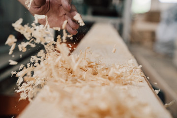 hand sweeps sawdust from a wooden beam - obrazy, fototapety, plakaty