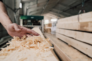 hand sweeps sawdust from a wooden beam