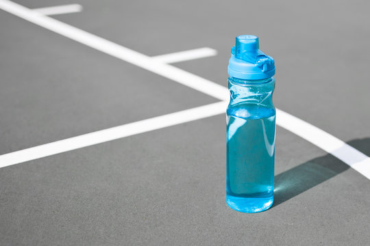 Drinking water and health concepts. Isolated bottle of water on basketball court. - Powered by Adobe