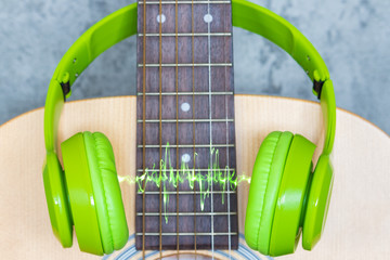 green headphone on acoustic guitar, music background