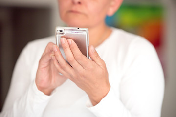 in the foreground the female hands are holding the phone, in the background you can see the smudged figure. fingers are moving across the screen of the phone.