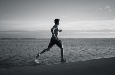 Fit muscular male running on the beach. Fitness workout concept.