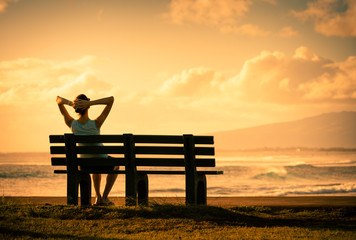 Young woman sitting back relaxing watching the beautiful sunset. 