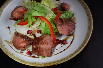 Meat hot salad with beef tenderloin, iceberg salad and garnet decorated with pomegranate