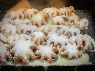 Big size of Octopus on takoyaki are cooked on the hot stove. Japanese appetizers