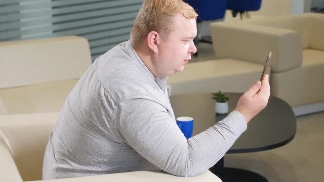 A man who is overweight talks on a video call phone