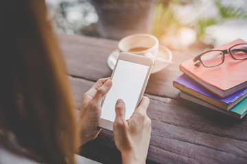 Close up hand holding young woman a smart phone with a blank white screen in a cafe, touching smartphone screen. Mockup portrait.