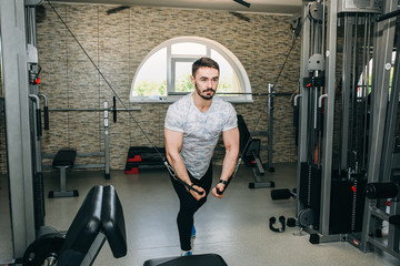 Bearded man is training in the gym with weights. Young guy in trainers and sports clothes is doing exercises for good muscles. Fitness personal trainer is at work. Sport motivation healthy lifestyle.