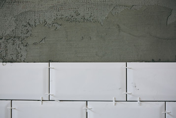 White tiles laid on the grey concrete. Maintenance repair works renovation in the flat. Restoration indoors. Work in process.