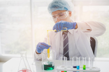 Scientist or researcher is looking at a liquid sample in a test tube with a pipette. Science,...